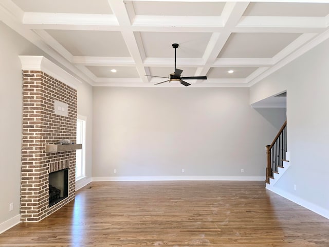 unfurnished living room featuring hardwood / wood-style flooring, beam ceiling, coffered ceiling, and a brick fireplace