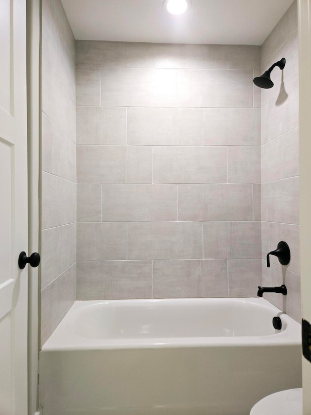 bathroom featuring toilet and tiled shower / bath