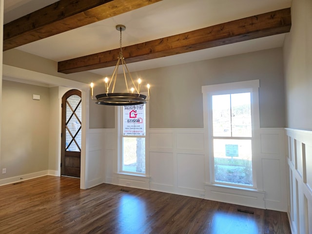 unfurnished dining area with beamed ceiling, dark hardwood / wood-style floors, and an inviting chandelier