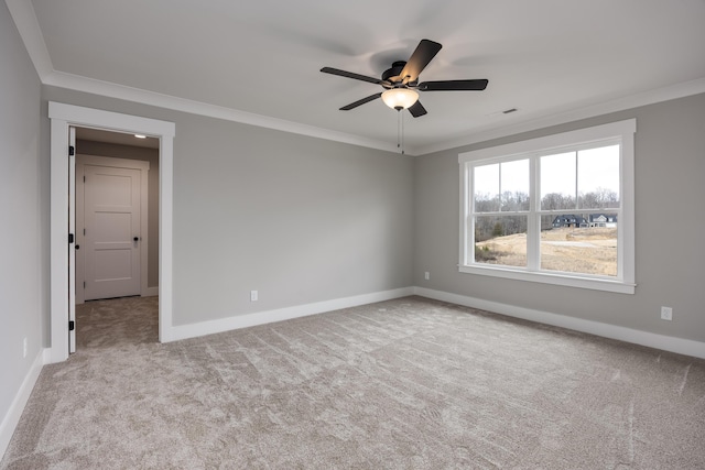 carpeted empty room featuring a ceiling fan, baseboards, and ornamental molding