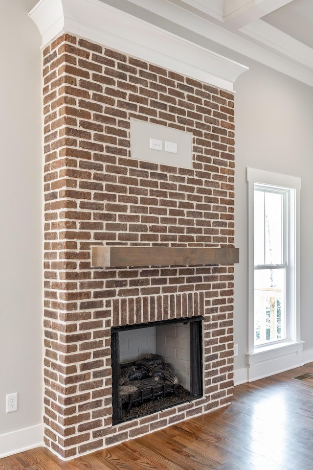 room details with a brick fireplace, wood finished floors, visible vents, and baseboards