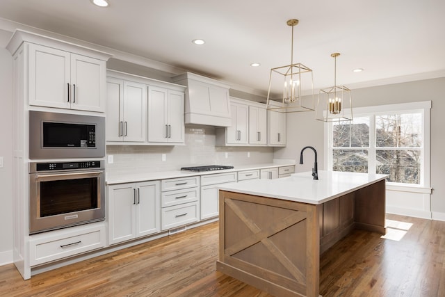 kitchen featuring oven, built in microwave, light countertops, gas stovetop, and a sink