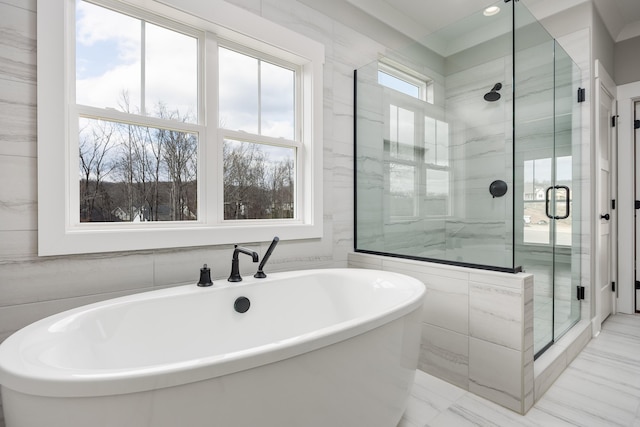 full bath featuring tile walls, a soaking tub, marble finish floor, and a stall shower