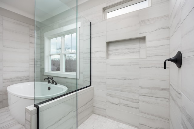 bathroom featuring a tile shower, a freestanding bath, and tile walls