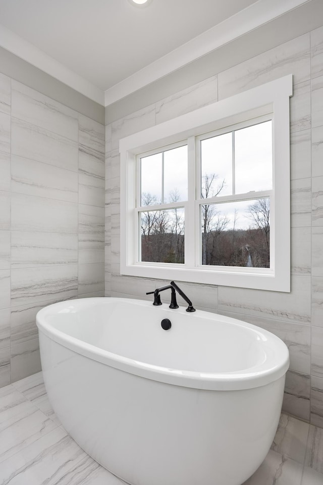 full bathroom featuring tile walls, a freestanding bath, and marble finish floor