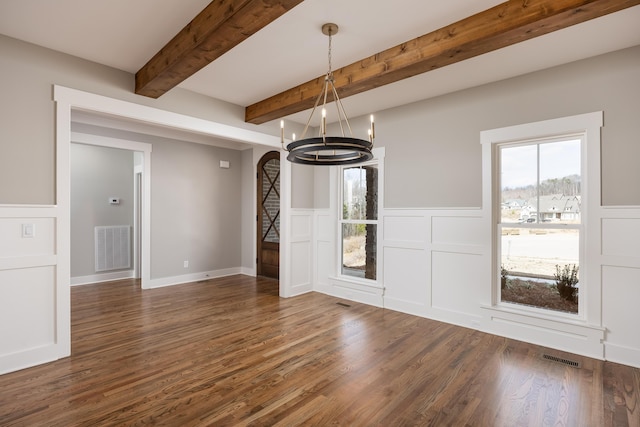 unfurnished dining area featuring beamed ceiling, wood finished floors, visible vents, and a chandelier