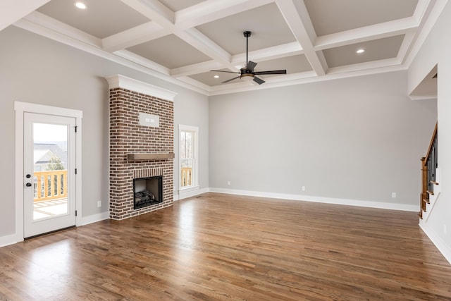 unfurnished living room featuring a wealth of natural light, stairway, wood finished floors, and a fireplace