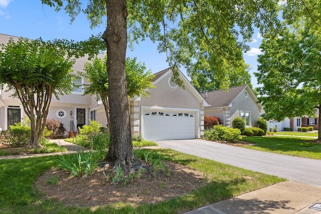 view of front of house with stucco siding, an attached garage, concrete driveway, and a front lawn