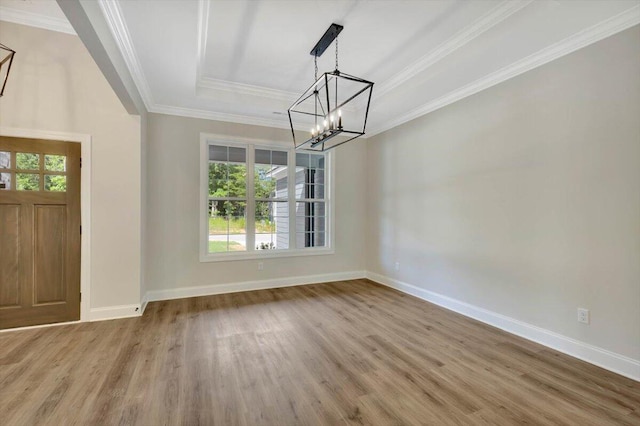 unfurnished dining area with ornamental molding, a raised ceiling, wood-type flooring, and an inviting chandelier