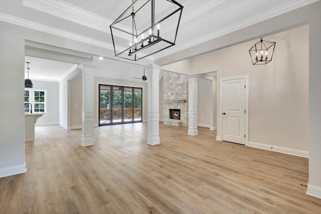 unfurnished living room with a fireplace, light hardwood / wood-style flooring, an inviting chandelier, and decorative columns