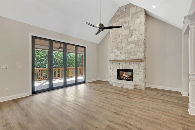 unfurnished living room featuring high vaulted ceiling, light hardwood / wood-style flooring, ceiling fan, and a stone fireplace