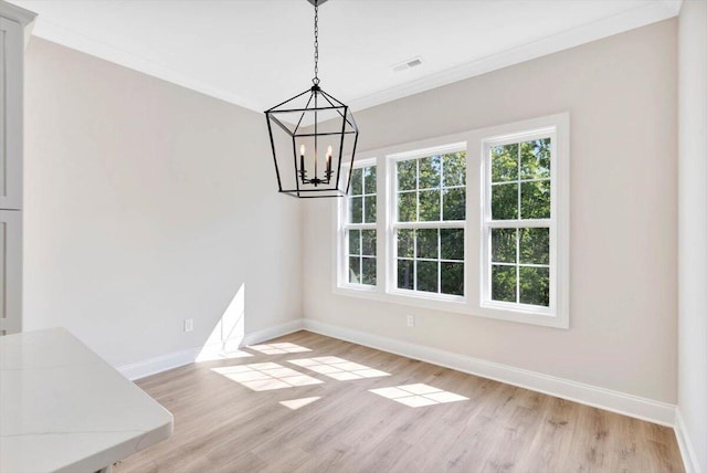 unfurnished dining area featuring light wood-type flooring, a chandelier, and crown molding