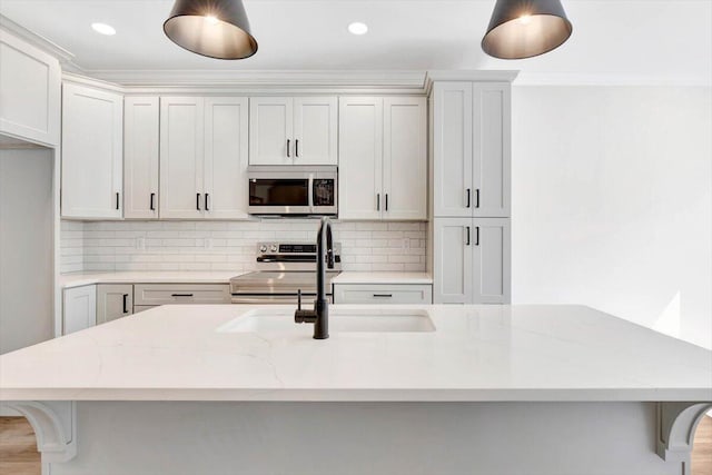 kitchen with light stone countertops, stainless steel appliances, and an island with sink