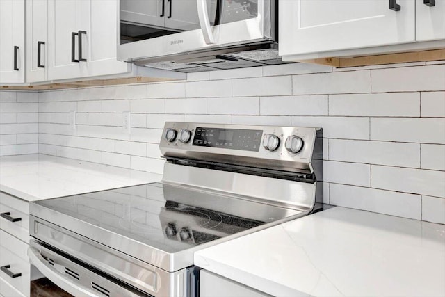 kitchen with white cabinets, appliances with stainless steel finishes, and decorative backsplash