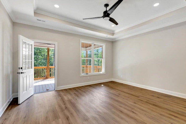 empty room featuring hardwood / wood-style floors, ceiling fan, a raised ceiling, and ornamental molding