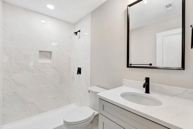 bathroom with vanity, toilet, and tiled shower