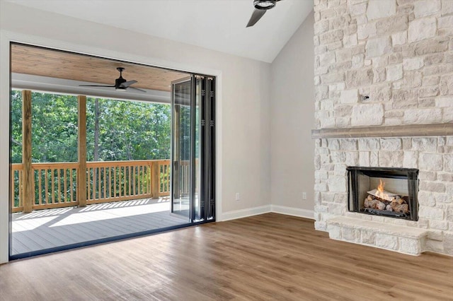 unfurnished living room featuring lofted ceiling, ceiling fan, a stone fireplace, and wood-type flooring