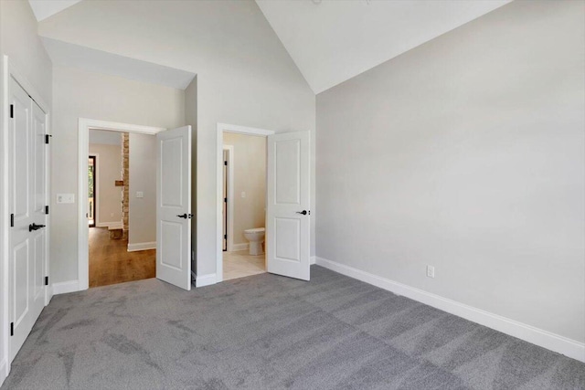 unfurnished bedroom featuring light carpet and high vaulted ceiling