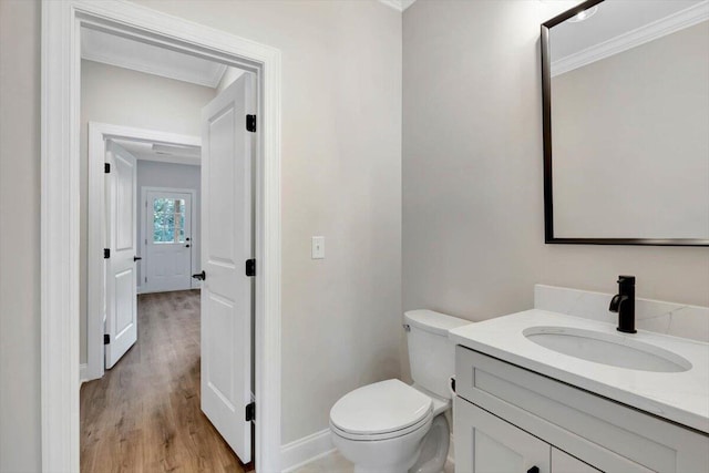 bathroom featuring vanity, toilet, ornamental molding, and wood-type flooring