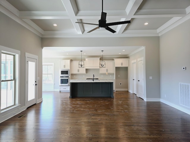 kitchen featuring built in microwave, oven, dark hardwood / wood-style flooring, white cabinetry, and an island with sink