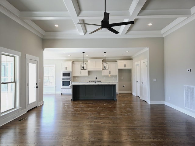 kitchen featuring visible vents, oven, built in microwave, white cabinets, and a sink