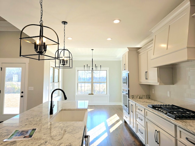 kitchen featuring dark hardwood / wood-style floors, hanging light fixtures, stainless steel appliances, sink, and light stone counters