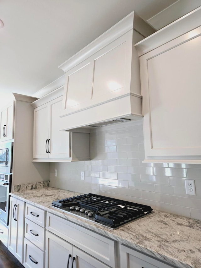 kitchen featuring premium range hood, white cabinetry, stainless steel appliances, and decorative backsplash