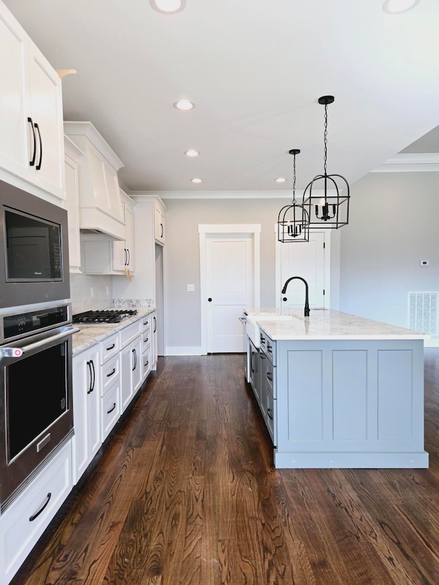 kitchen featuring a center island with sink, appliances with stainless steel finishes, dark wood-type flooring, sink, and white cabinets