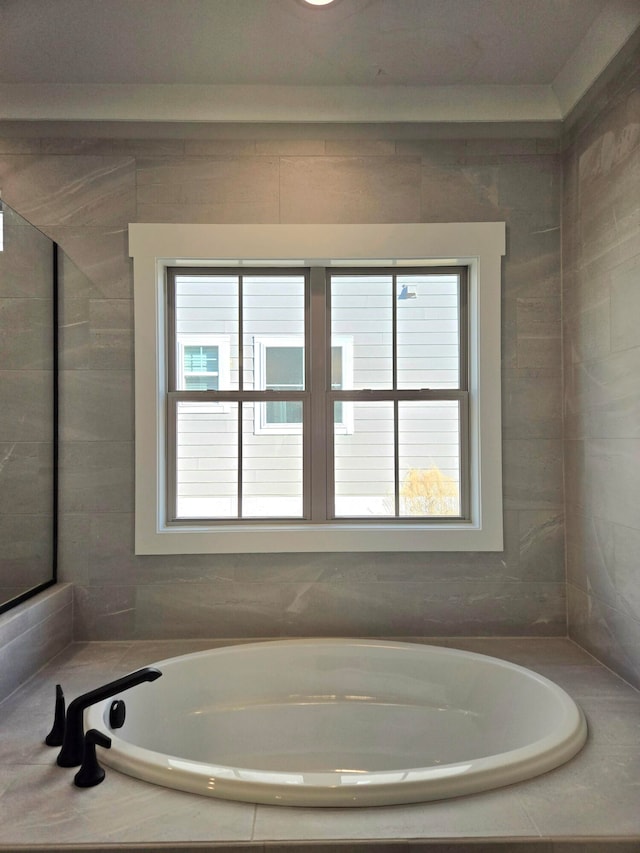 bathroom featuring tiled bath and a healthy amount of sunlight