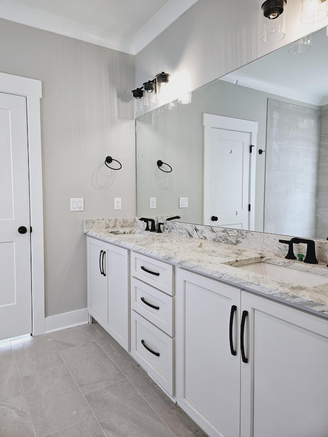 full bath with double vanity, crown molding, baseboards, and a sink