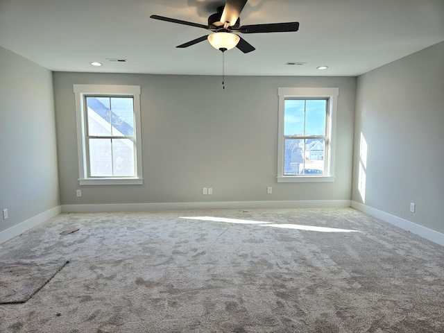 unfurnished room with carpet flooring, visible vents, and a wealth of natural light