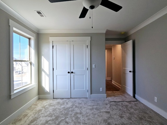 unfurnished bedroom featuring crown molding, ceiling fan, light carpet, and a closet