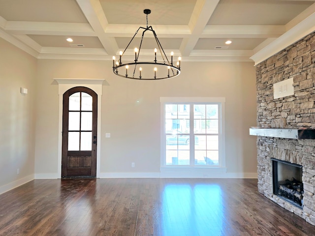 foyer featuring beam ceiling, a stone fireplace, an inviting chandelier, and dark hardwood / wood-style floors