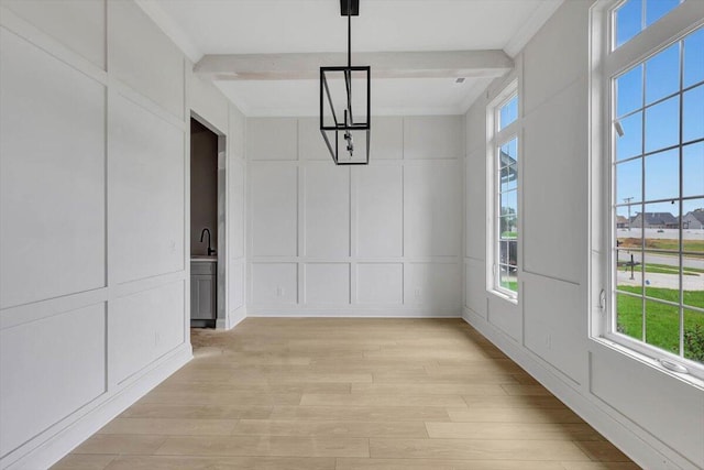 interior space featuring ornamental molding, light hardwood / wood-style floors, and beamed ceiling