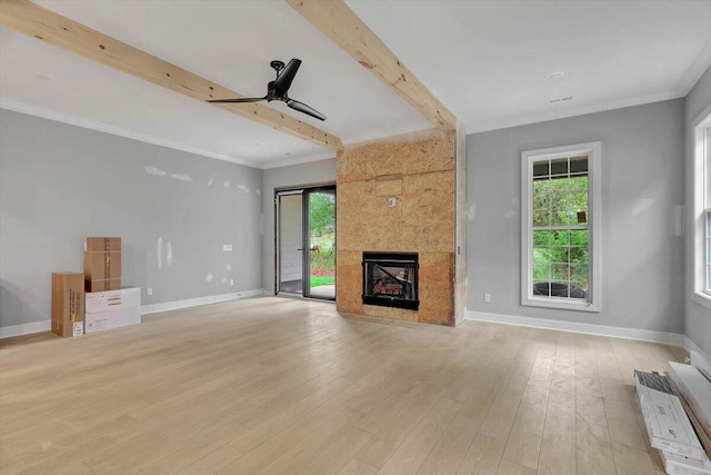 unfurnished living room featuring light hardwood / wood-style floors, beam ceiling, ornamental molding, a large fireplace, and ceiling fan