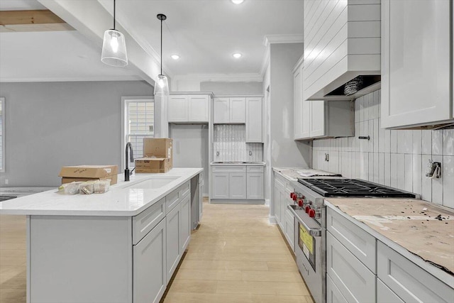 kitchen with sink, decorative light fixtures, a kitchen island with sink, light hardwood / wood-style flooring, and appliances with stainless steel finishes