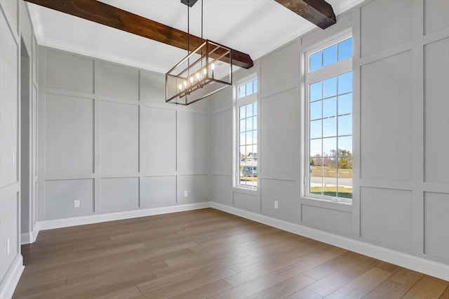 unfurnished dining area featuring beam ceiling, wood-type flooring, and a chandelier