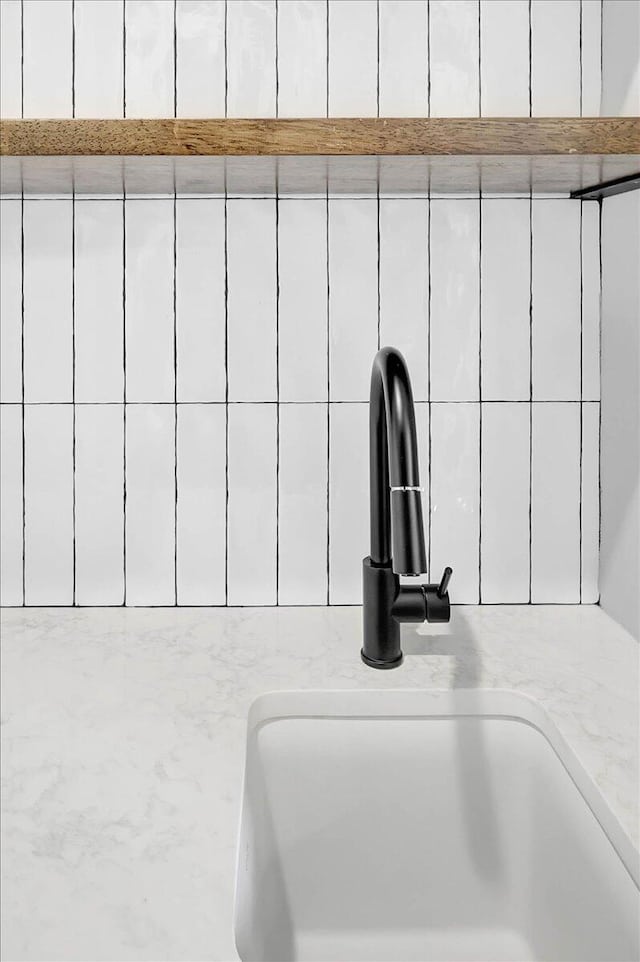 details with white cabinetry, light stone countertops, and sink