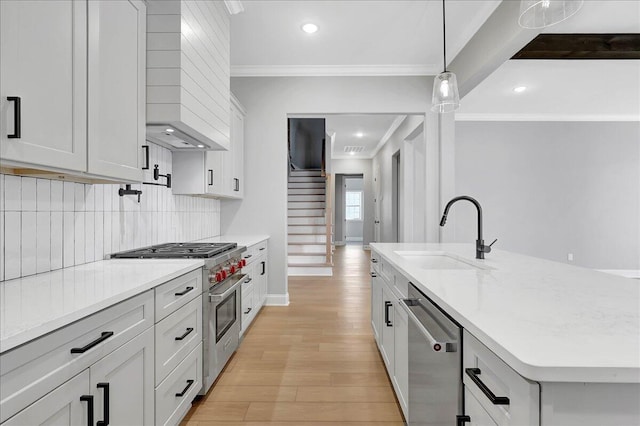 kitchen with sink, appliances with stainless steel finishes, an island with sink, light stone countertops, and white cabinets