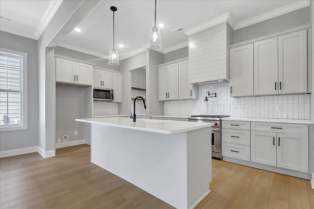 kitchen with white cabinetry, pendant lighting, stainless steel appliances, and an island with sink