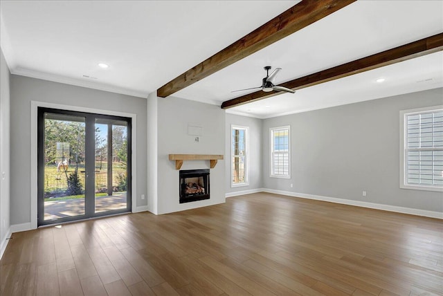 unfurnished living room featuring wood-type flooring, ornamental molding, ceiling fan, and beam ceiling