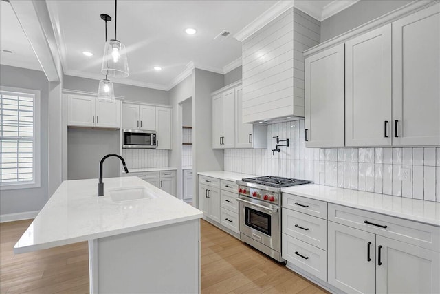 kitchen featuring sink, appliances with stainless steel finishes, an island with sink, light stone countertops, and white cabinets