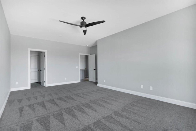 unfurnished bedroom featuring dark carpet, ceiling fan, and a spacious closet