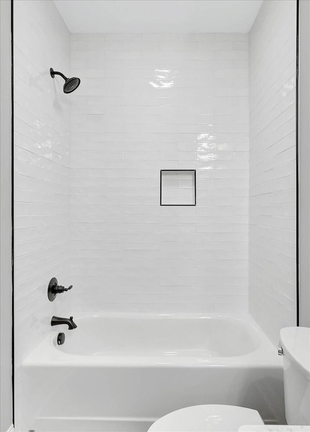 bathroom featuring tiled shower / bath combo and toilet