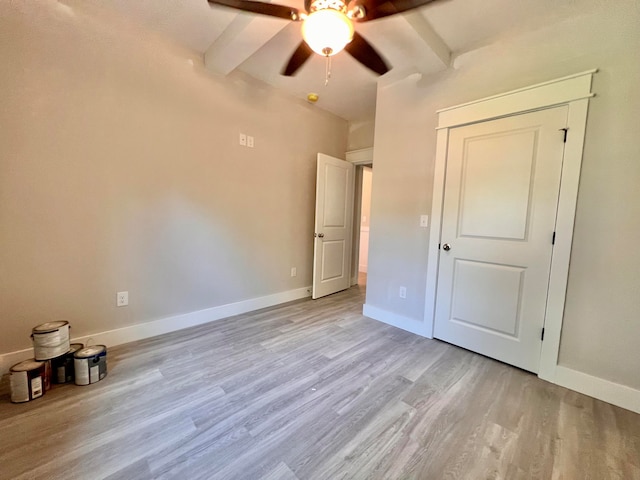 unfurnished bedroom featuring beamed ceiling, light hardwood / wood-style floors, and ceiling fan