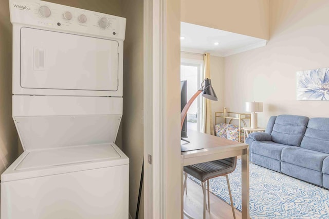 laundry room with stacked washing maching and dryer and crown molding