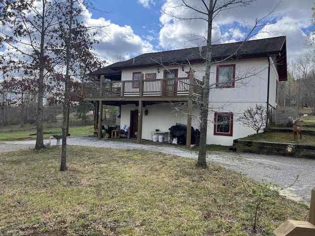 back of property with a deck and a yard