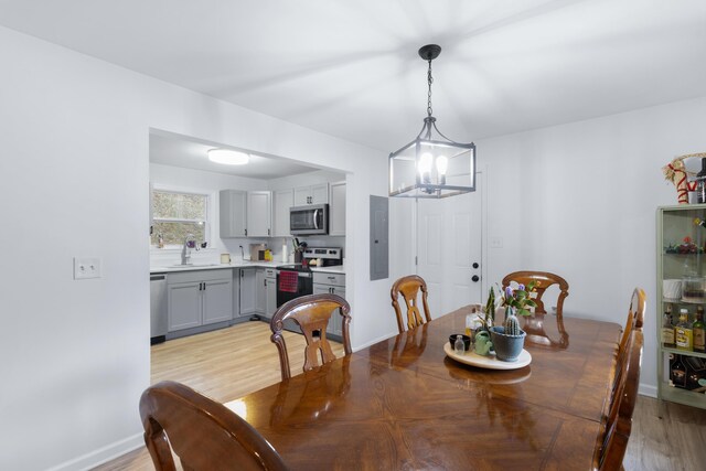 dining area featuring electric panel, an inviting chandelier, sink, and light wood-type flooring