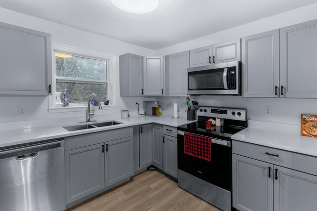 kitchen featuring light hardwood / wood-style floors, gray cabinetry, sink, and appliances with stainless steel finishes