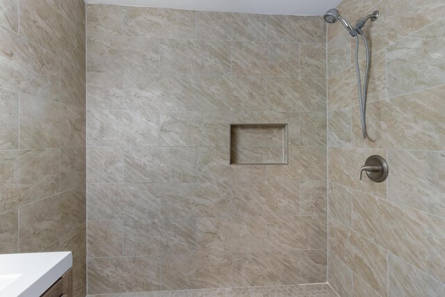 bathroom with vanity and a tile shower